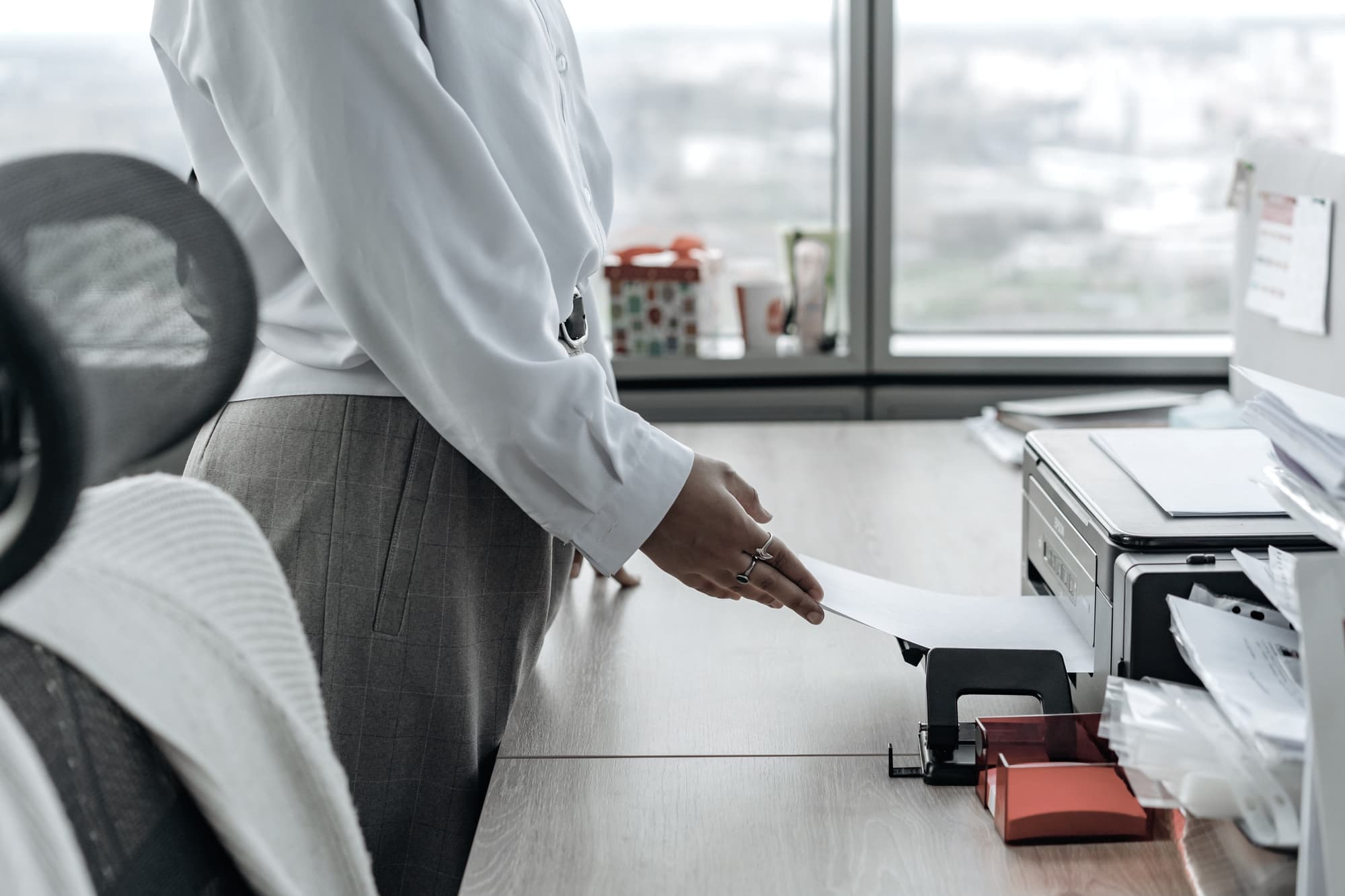 A person using a printer at a desk in a bright office